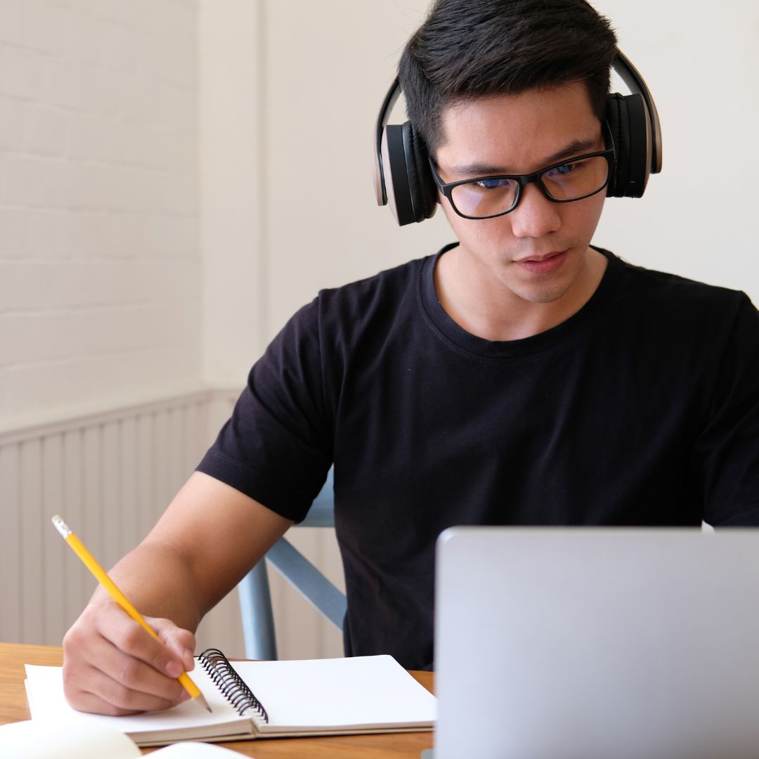 Man taking notes looking at computer