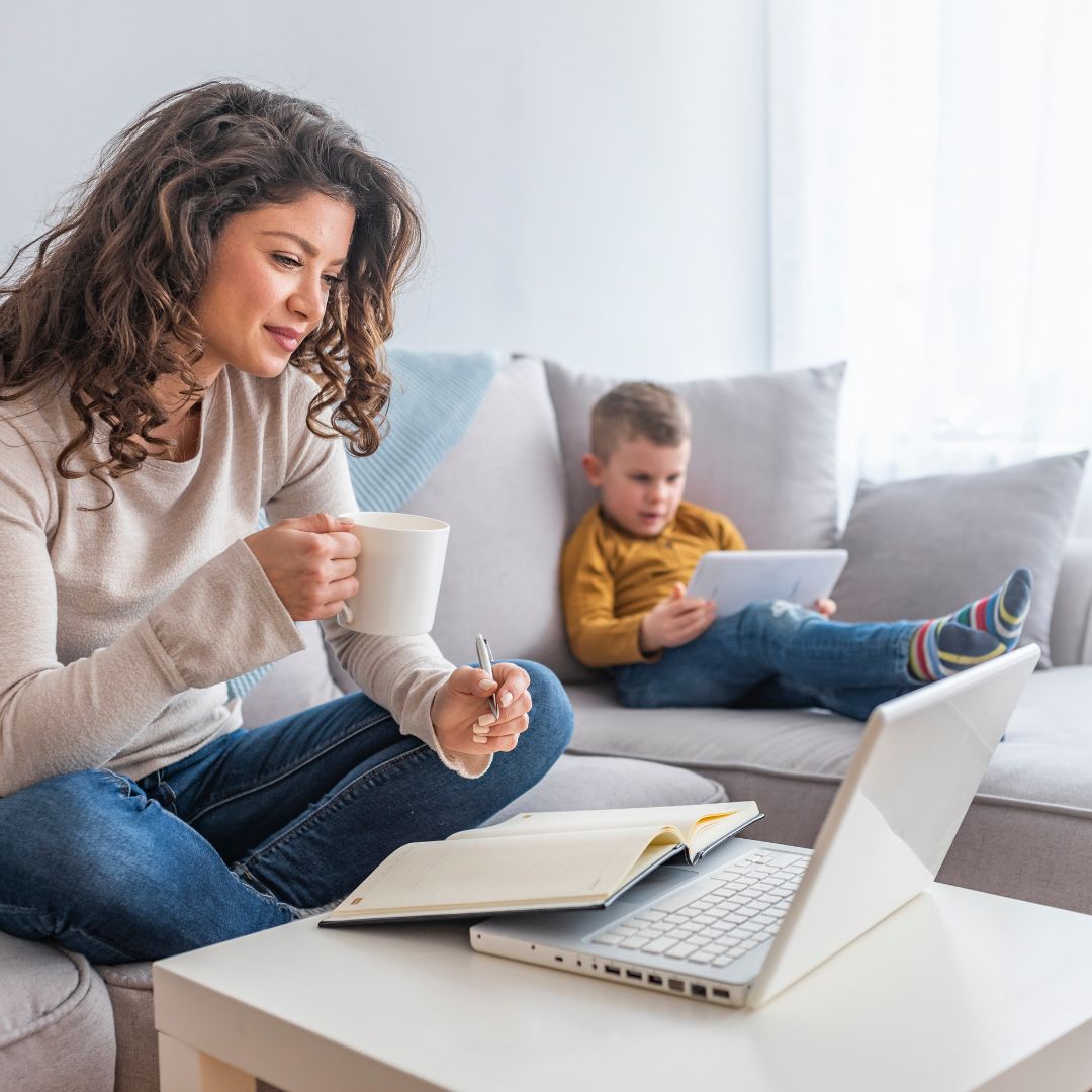 Mom looking at computer while her son is sitting on the couch with her